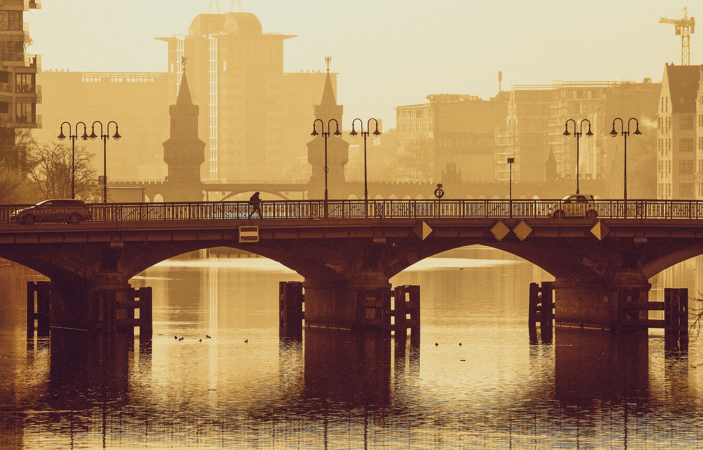 Amber Bridge Reflection - Warm bridge reflection over water at sunset. Museum-grade framed artwork by Veriando Studio.