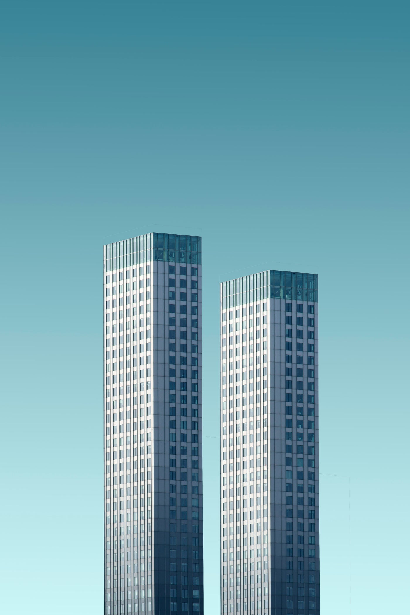 Two White Towers - Two pale towers isolated against a turquoise sky. Museum-grade framed artwork by Veriando Studio.