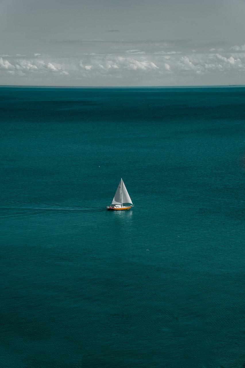 Small Sail in Vast Teal - Small sailboat surrounded by open teal sea. Museum-grade framed artwork by Veriando Studio.