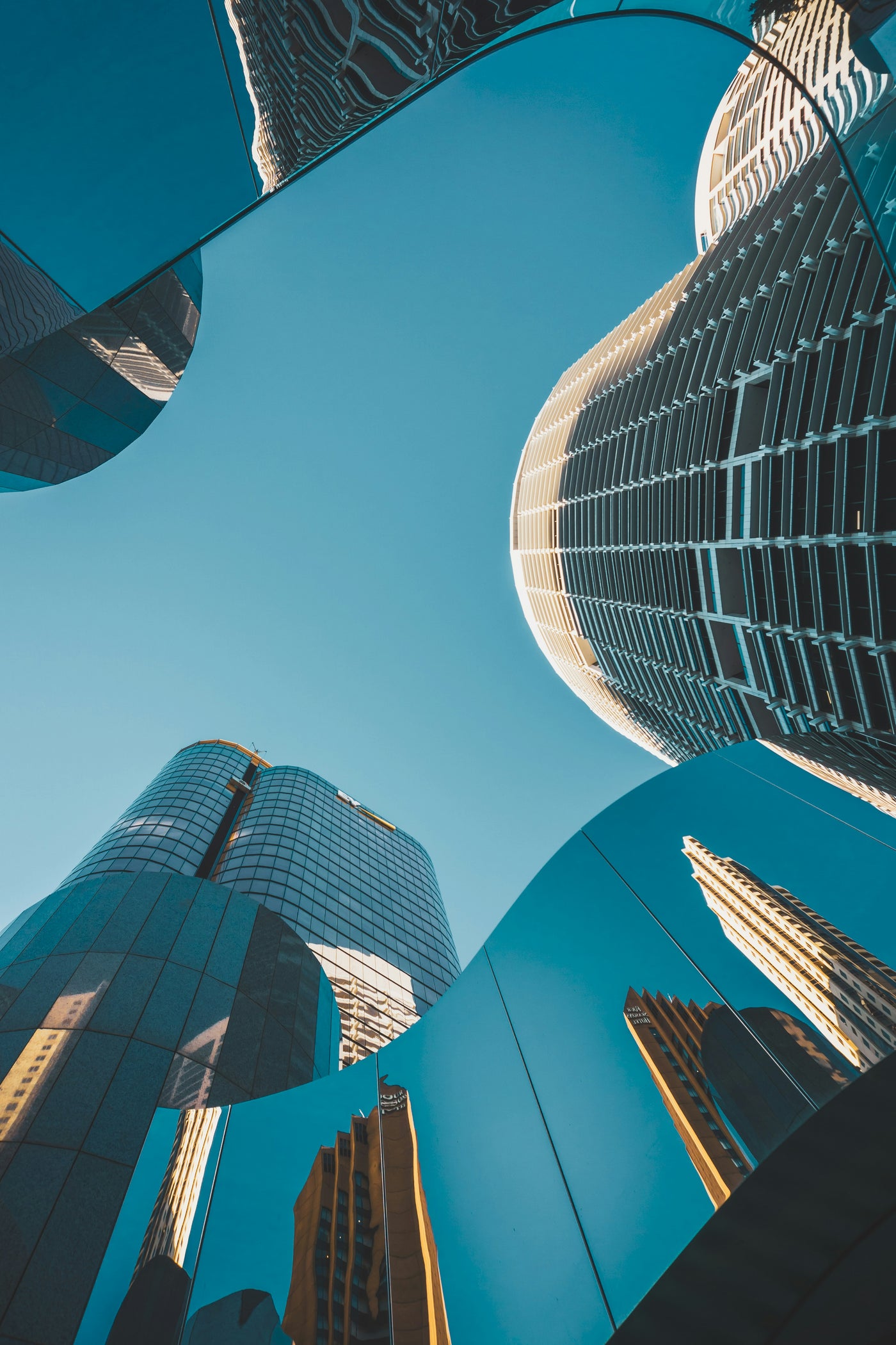 Blue Sky Between Towers - Upward view between curving glass towers and blue sky. Museum-grade framed artwork by Veriando Studio.