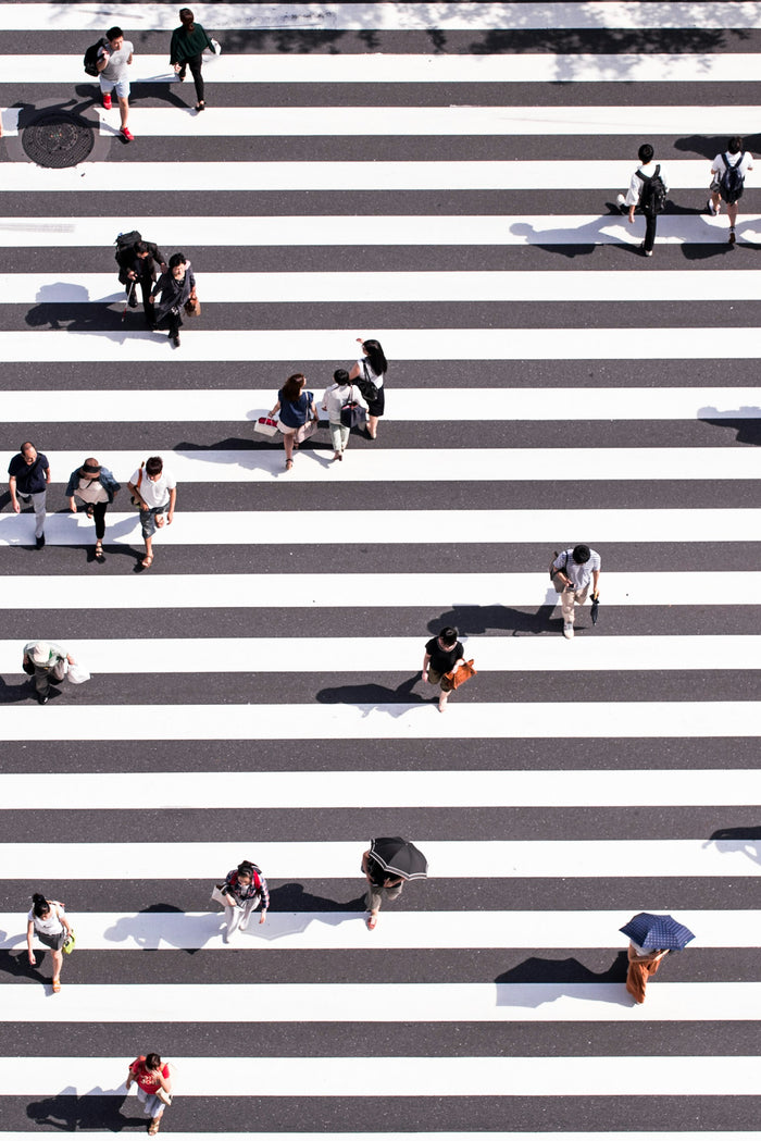 Crossing Lines - Overhead pedestrian crossing with small human figures. Museum-grade framed artwork by Veriando Studio.