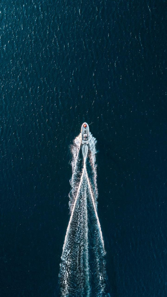 White Wake in Blue Water - Boat wake seen from above in dark water. Museum-grade framed artwork by Veriando Studio.